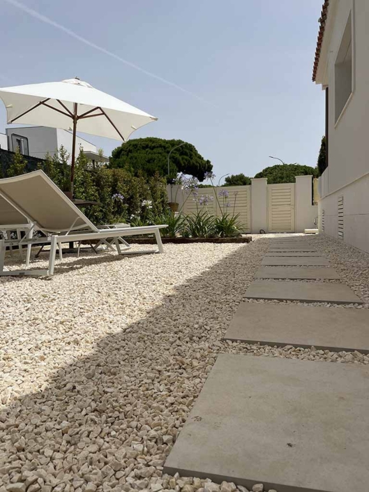 rehabilitacion-integral-casa-unifamiliar-castelldefels-jardin jardin tumbuna parasol blanco suelo piedra plantas