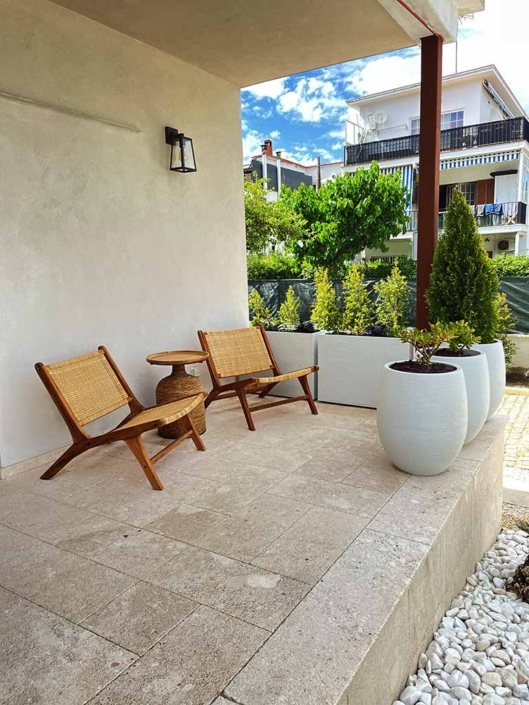 rehabilitacion-integral-casa-unifamiliar-castelldefels-porche-entrada porche casa mesa butacas madera plantas macetas grandes blancas